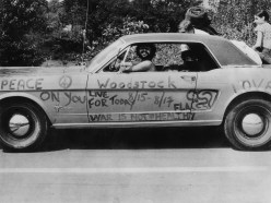 A black and white photo of a car decorated for the Woodstock music festival