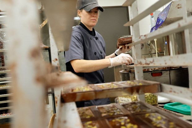 Store manager Kayla Floyd slides bars of dark chocolate with pistachios and sea salt onto a cooling rack at 5150 Chocolate in Delray Beach on Monday, July 15, 2024. (Amy Beth Bennett/Sun Sentinel)