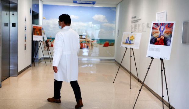 A doctor walks by artwork on display at Cleveland Clinic in Weston on Wednesday, June 26, 2024. (Carline Jean/South Florida Sun Sentinel)