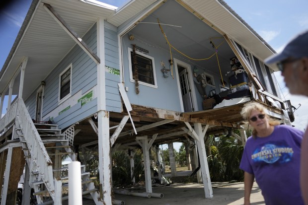 FILE - Jim, right, and Sally Johnson survey the damage to their waterfront home, stilted to older code height requirements, in Horseshoe Beach, Fla., Sept. 1, 2023, two days after the passage of Hurricane Idalia. Whether sacrificing a beach for a seawall or using nature-based solutions like wetlands that buffer against extreme weather, coastal communities are facing the increasingly difficult choice between staying and going. They're asking themselves "whether or not we can protect the infrastructure in place, and if we do that, for how long and at what cost," said Alyssa Mann, climate resilience project director for the California chapter of the Nature Conservancy. (AP Photo/Rebecca Blackwell, File)