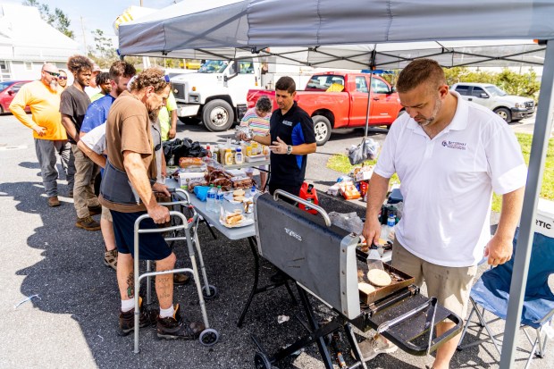 Dan Wilson, right, owner of Betterway Claim Adjusters, works with David Rodriguez, center, to hand out hotdogs and hamburgers to residents in Perry, Fla., on Thursday, Aug. 31, 2023. Taylor County felt the full impacts of Hurricane Idalia, which made landfall near Category 4 strength on Wednesday morning. (Patrick Connolly/Orlando Sentinel)